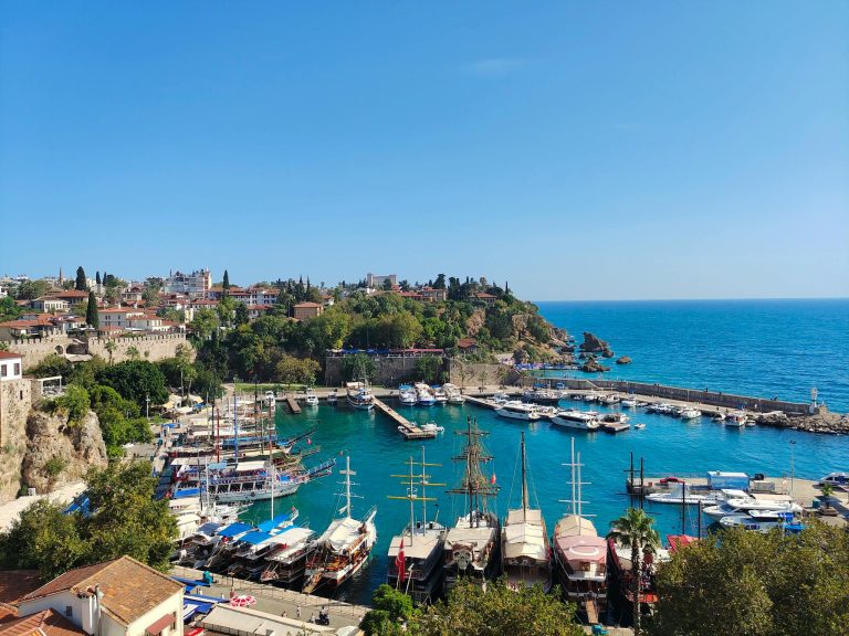 A breathtaking view of Antalya's harbor with boats and clear blue sea under a bright summer sky.