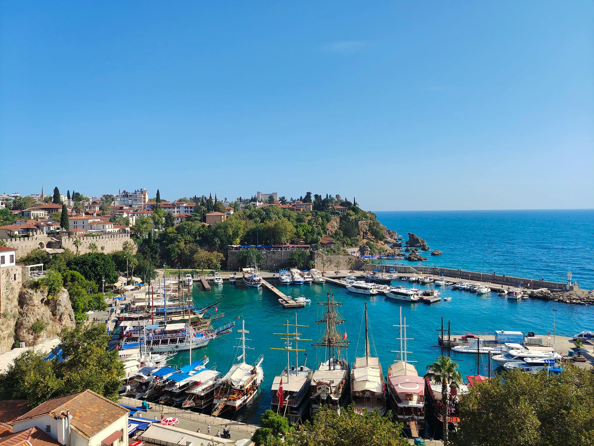A breathtaking view of Antalya's harbor with boats and clear blue sea under a bright summer sky.